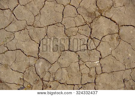 Gray Natural Background. Cracks In Dry Soil During A Drought.