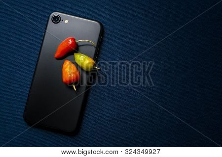 Hot Chilis On Modern Mobile Phone With Reflecting Silk Background Close Up Elegant Uniqe Stock Photo