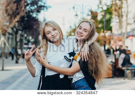 Happy Brightful Positive Moments Of Two Stylish Girls Hugging On Street In City. Closeup Portrait Fu