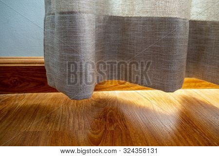 Cotton Curtain Near The Wooden Floor On Which The Golden Sunlight Reflection
