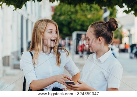 Happy   Moments Of Two Stylish Girls Hugging And Looking At The Phone, Discussing Something On The S