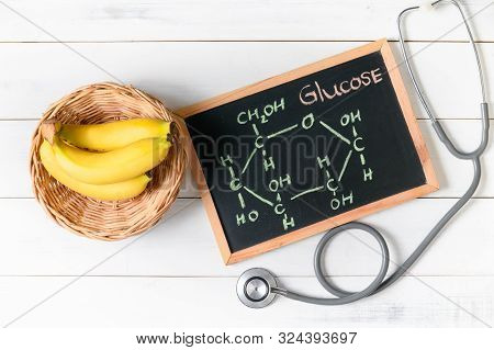 Glucose Molecule On Blackboard With Banana And Stethoscope On Wooden White Background, Diet And Food