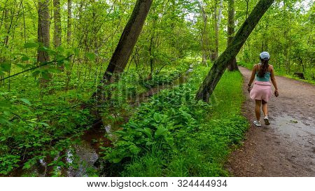 Middle Age Woman With Pink Sweater Walking On Trail In National Park