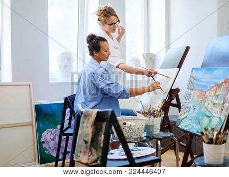 Creative painter and her protege working in a studio