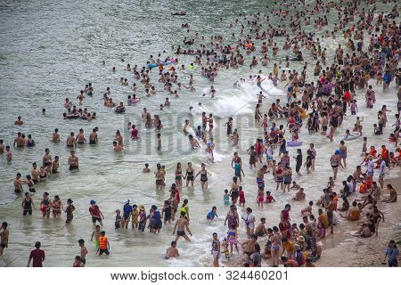 Many Chinese Tourists On The Beach Swim In The Waves