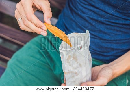 Man Eat Fried Sweet Potatoes In The Park. Junk Food Concept