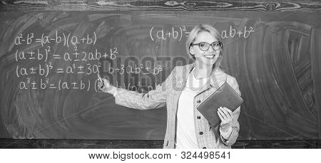 Teacher Smart Woman With Book Explain Topic Near Chalkboard. School Teacher Explain Things Well And 