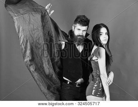 Attractive Demon Concept. Couple On Strict Face Play Role Game. Vampire In Cloak And Sexy Devil Girl