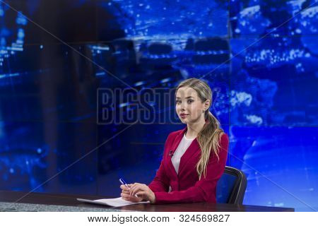 News Anchor In The Tv Studio . Beautiful Girl Reading The News, On A Blue Screen Background