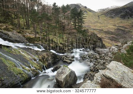 Beautiful Landscape Image Of Ogwen Valley River And Waterfalls During Winter With Snowcapped Mountai