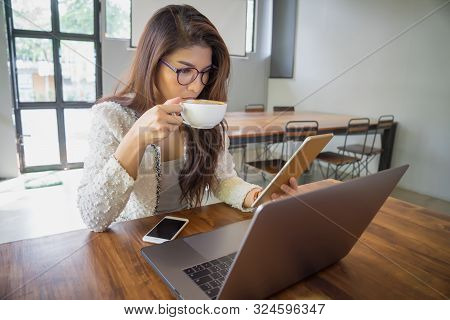 Young Business Woman Holding Tablet Computer And Dringking Coffee In Coffee Shop.
Asian Girl Using L