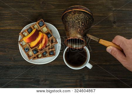 Belgian Waffles With Fruit And Berries. Male Hand Pours Coffee From A Coffee Pot. Top View