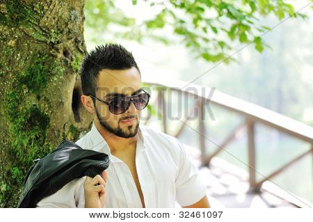 魅力男性持有他的外套在他的肩上