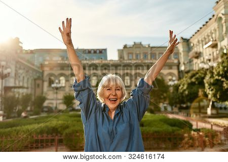 Age Is No Barrier. Portrait Of Happy And Beautiful Senior Woman Raising Hands Up And Smiling While S