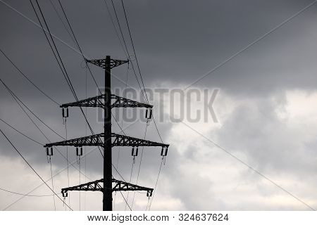 High Voltage Tower Silhouette With Electrical Wires On Storm Sky Background With Dark Clouds. Electr