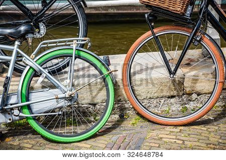 Bicycles With Blak, Green And Orange Tires On Brick Straat
