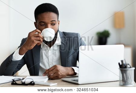 African American Man Drinking Coffee While Working On Laptop In Modern Office, Panora, A With Copy S