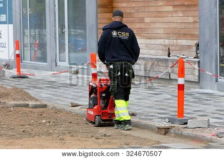 Copenhagen, Denmark - September 4, 2019.: Rear View Of A Male Worker Using A Red Vibratory Plate Com