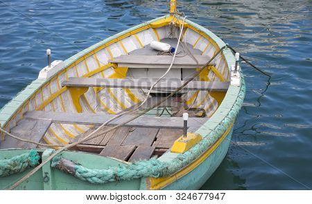 An Old White And Turquoise Wooden Rowing Boat Is Empty At Mooring In The Mediterranean Sea. Typical 