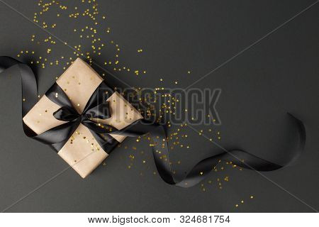 Gift Or Present Box And Gold Stars Confetti On Black Table Top View. Flat Lay Composition For Birthd