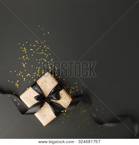 Gift Or Present Box And Gold Stars Confetti On Black Table Top View. Flat Lay Composition For Birthd