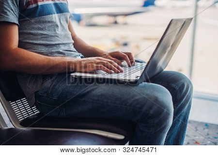 Cropped Image Of A Man Using Laptop To Write Emails In Airport Terminal