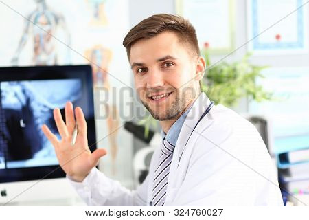 Portrait Of Smiling Doc Posing In Hospital Cabinet. Smiling Surgeon Wearing Medical Coat. X-ray Pict