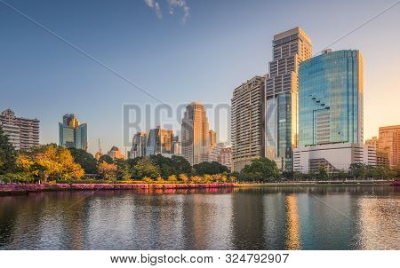 City Park With Lake Under Skyscrapers At Sunrise. Benjakiti Park In Bangkok, Thailand