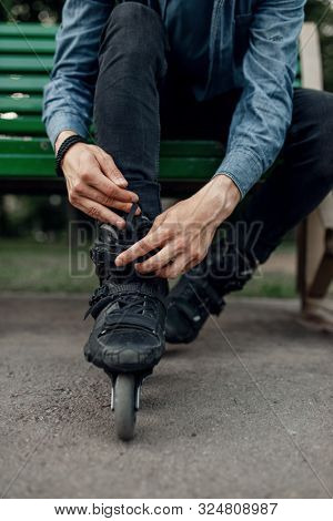 Roller skating, male skater puts on skates in park