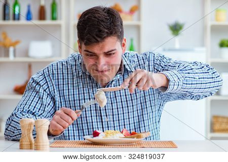 Man eating tasteless food at home for lunch