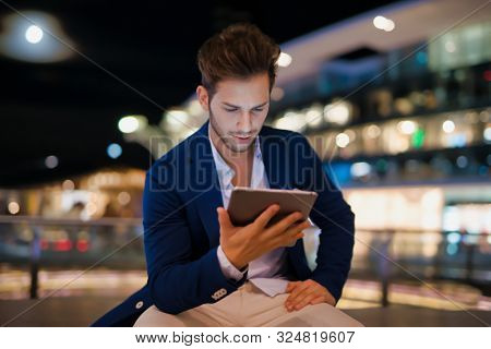 Portrait of man using his tablet in a city at night