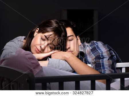 задумчивая пара смотрит на спящего ребенка