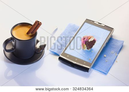 A Cup Of Espresso With A Tube Of Cinnamon. Dessert On A Paper Napkin In A Smartphone. Chocolate Past