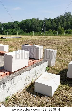 The Worker Begins The First Row Of Masonry Construction In White Gas Blocks.