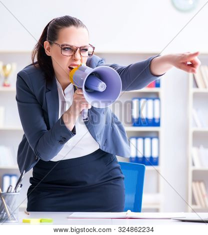 Angry businesswoman yelling with loudspeaker in office