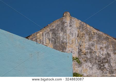 Wall Of An Old House, Creating A Tringle With The Roof Line. Weathered Facade, Blue Wall Of A House 