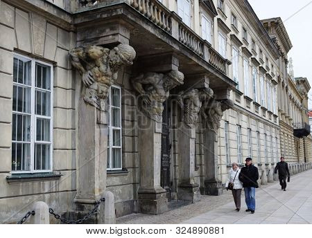Warsaw - September 2013: Atlas supporting a balcony. People walk past the building. The central part of the city.