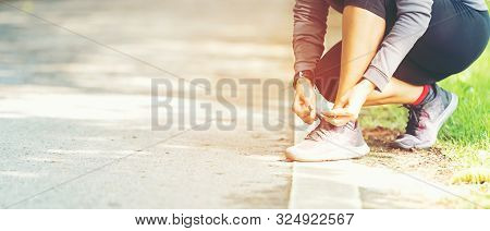 Running Woman Tying Laces Of Running Shoes Before Jogging Through The Road In The Workout Nature Par