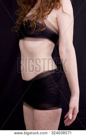 Three Quarter View Of Anonymous Pale Freckled Red Haired Woman Torso With Arms At Side Against Black