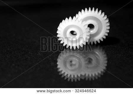 Several White Plastic Gears On A Black Mirror Background. Mechanical Repair. Fix. Reflection. Repair