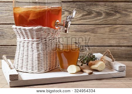 Fresh Homemade Kombucha Fermented Tea Drink In A Jar With Faucet And In A Cup On A White Tray On A W