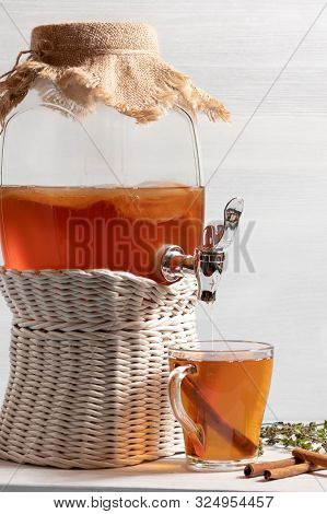 Fresh Homemade Kombucha Fermented Tea Drink In A Jar With Faucet And In A Cup On A White Tray On A W