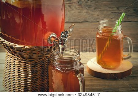 Fresh Homemade Kombucha Fermented Tea Drink In Jar With Faucet And In Cans-mugs On Wooden Background