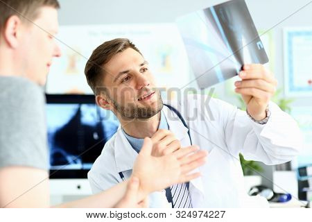 Portrait Of Doctor Examining Radiogram Picture. Smiling Physician Pleased With Results Of Treatment.
