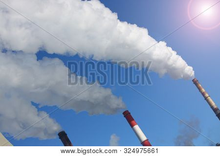 White Smoke Comes From Pipes Against Blue Sky. Problem Harmful Emissions And Air Pollution Of Centra