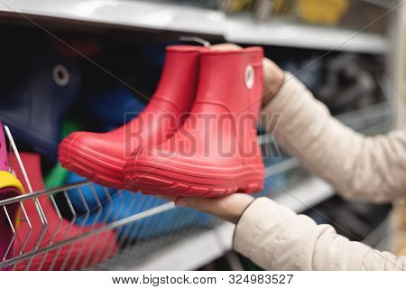 Woman Is Buying A New Galoshes Shoes In A Shop.