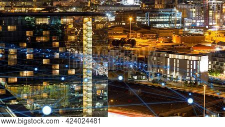 Glowing blue network of connections against view of cityscape at night. global networking and connection technology concept