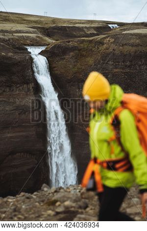Woman in a green jacket at the Haifoss waterfall, Iceland