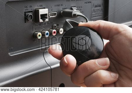 Carrara, Italy - June 18, 2021 - Woman Show A Google Chromecast Device Connected To A Tv