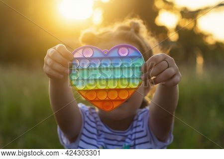 The Child Plays With A Colorful Rainbow Game Of Poppit. Silicone Fidget Close-up.